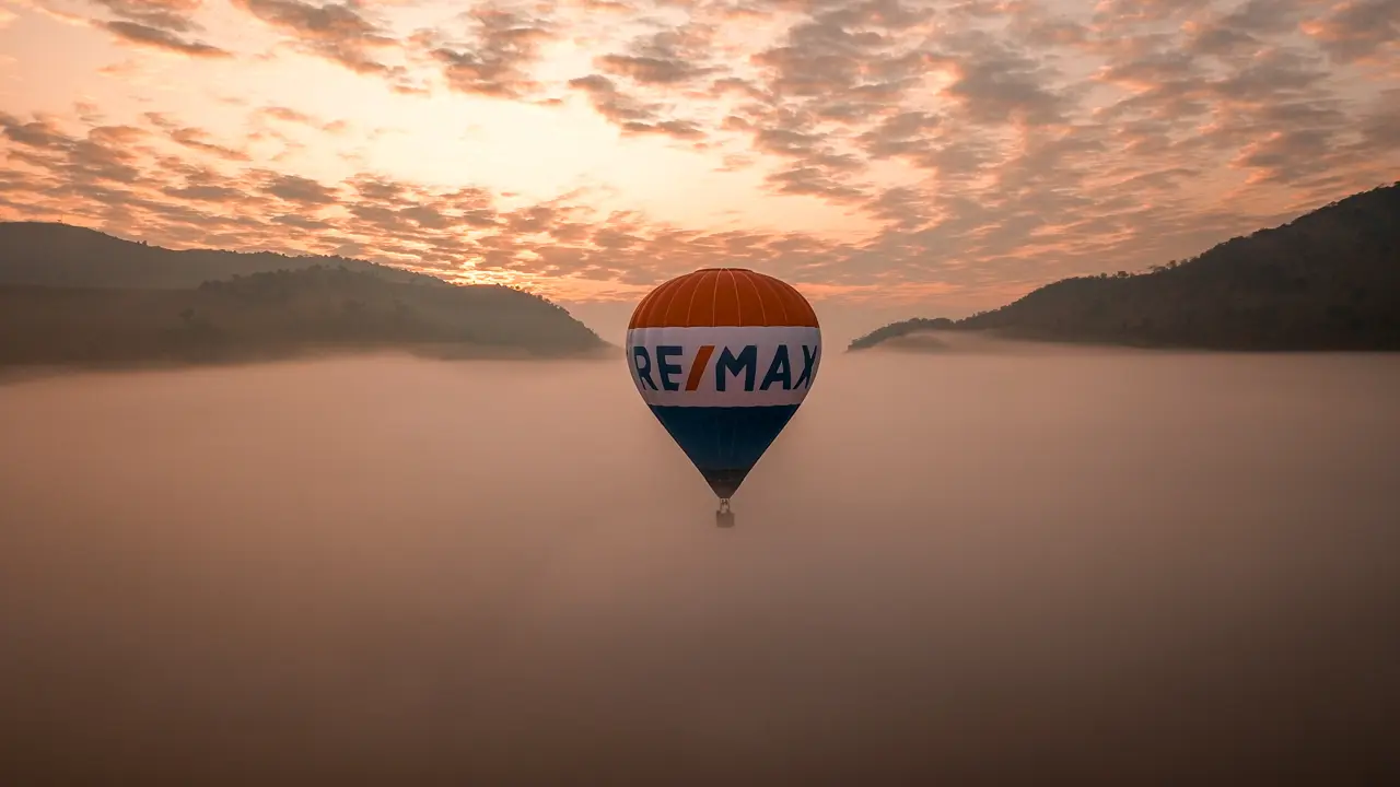 RE/MAX hot air balloon floating above morning fog at sunrise